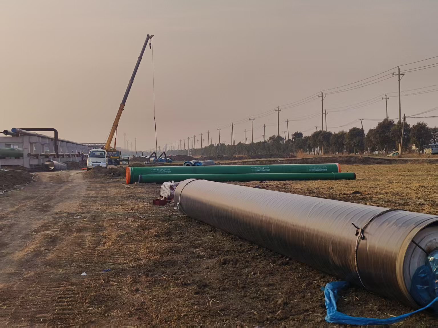 Large-diameter coated steel pipe staged at an industrial yard for shipment to an LNG project